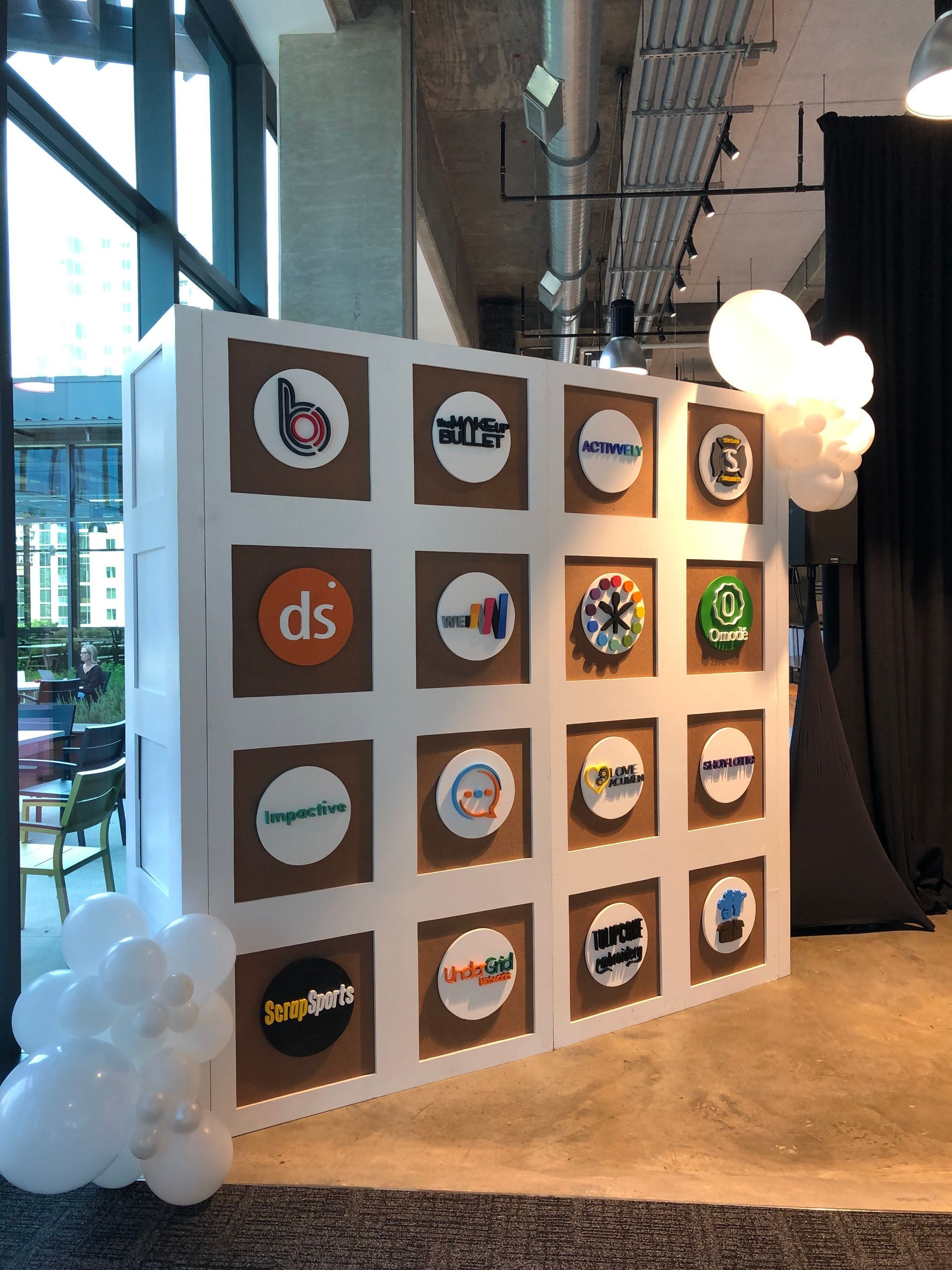A wall with logos on it is surrounded by balloons
