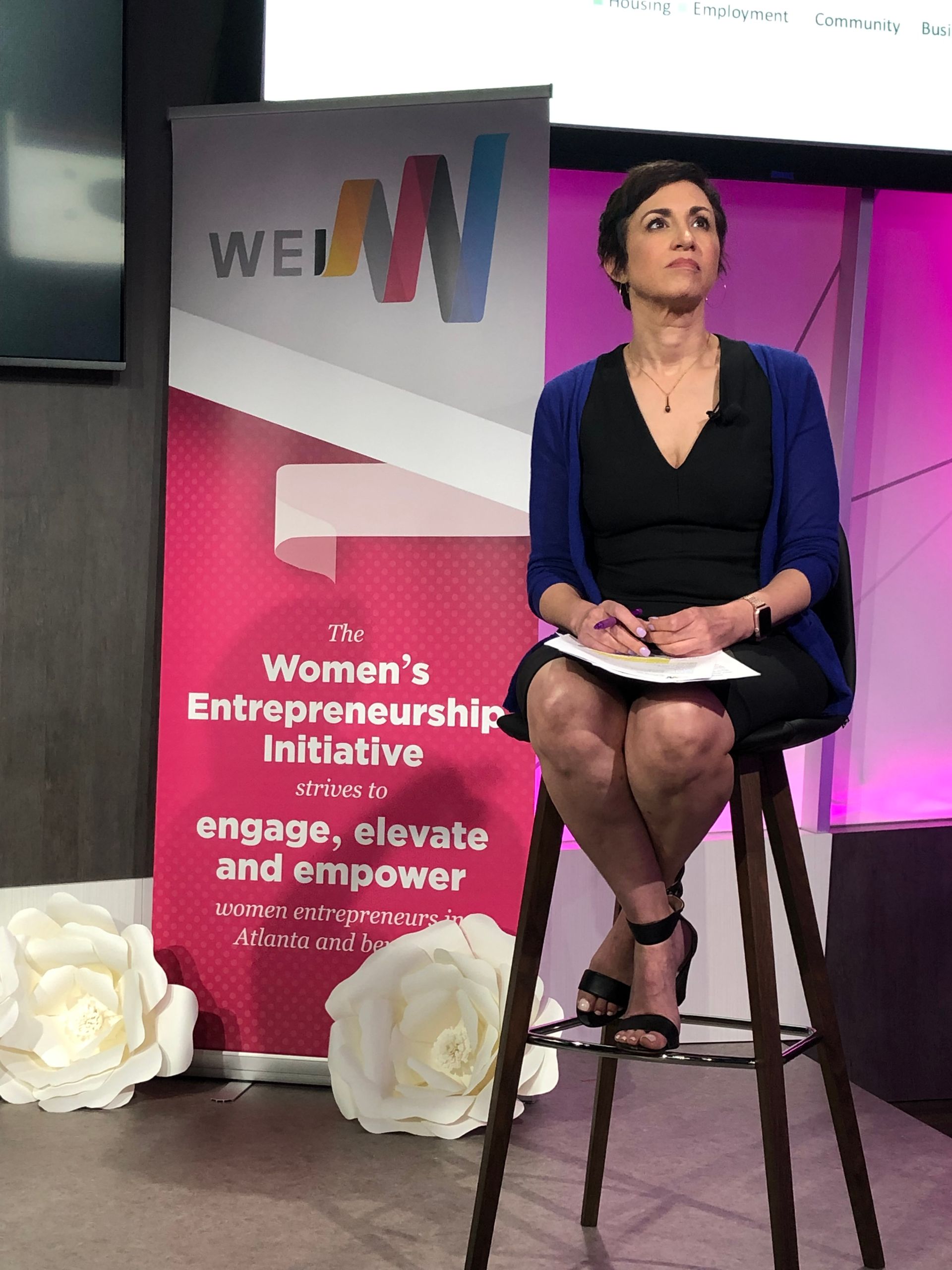 A woman is sitting on a stool in front of a sign that says women 's entrepreneurship initiative