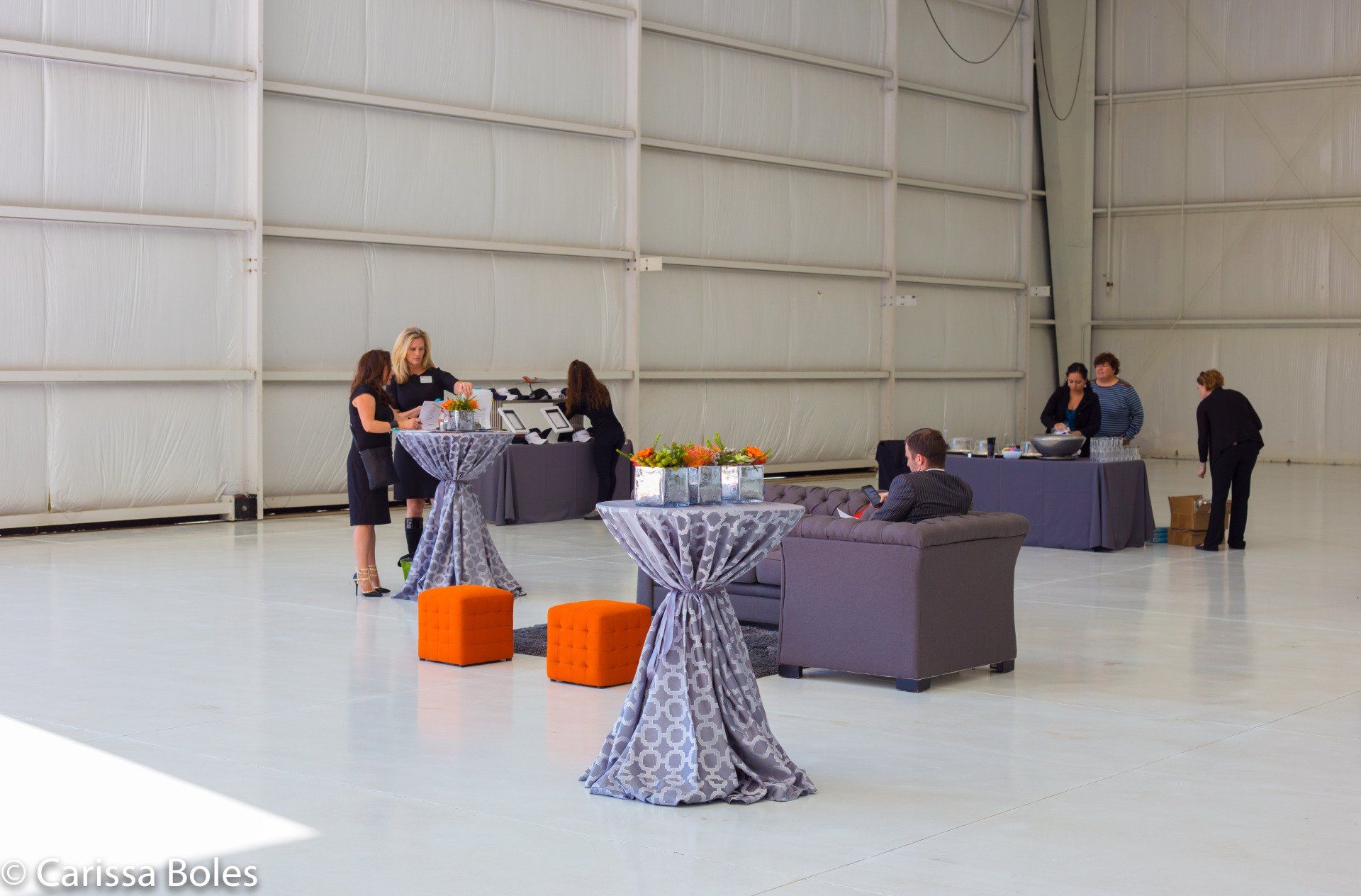 a group of people are standing around tables in a large room .
