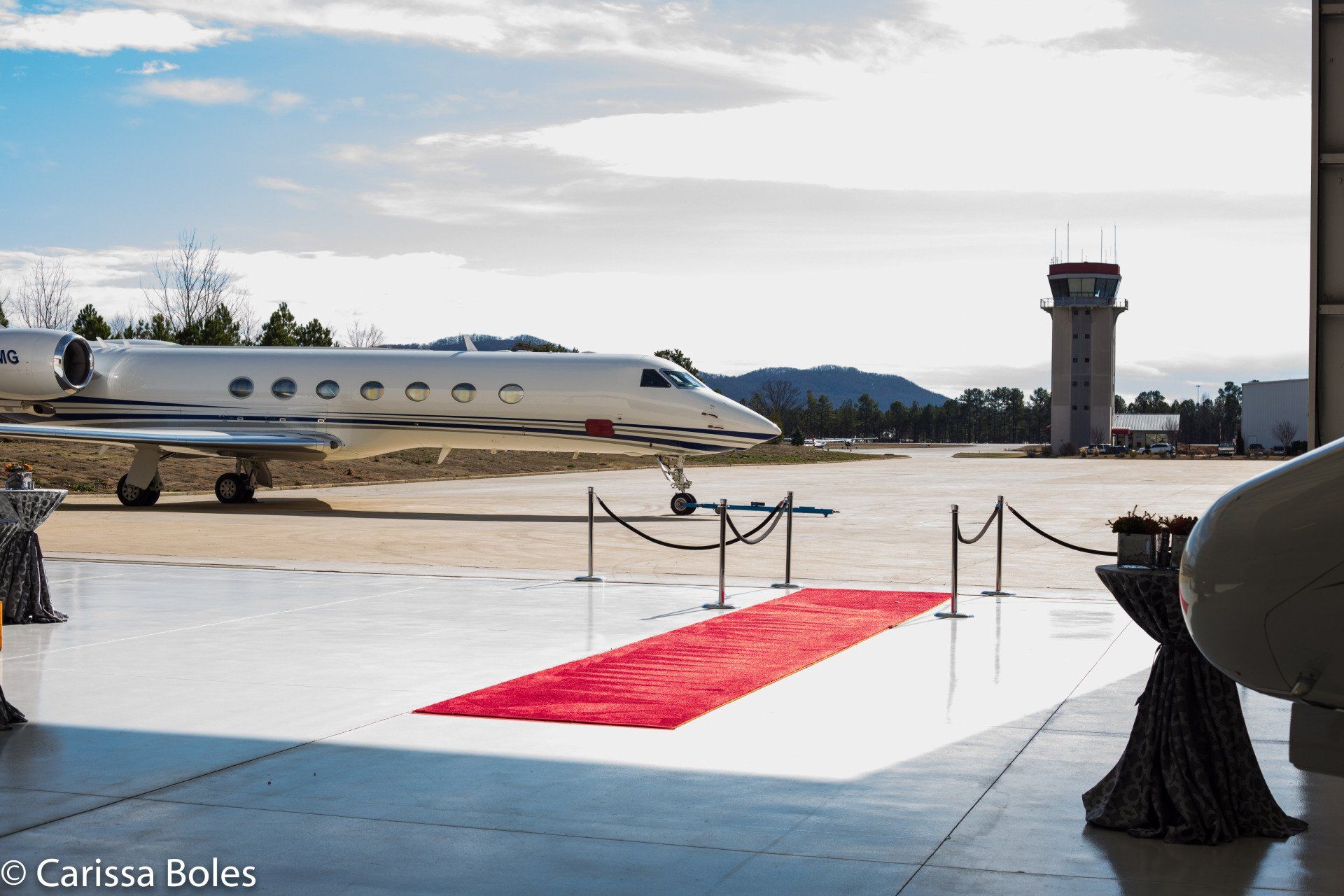 A red carpet is leading to a private jet on a runway.