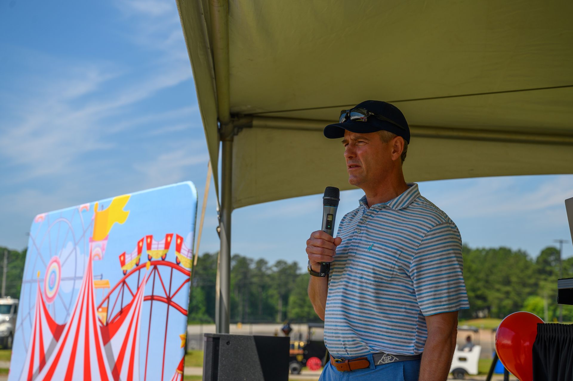 A man is standing under a tent holding a microphone.