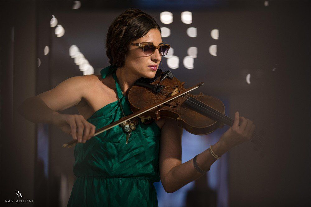 A woman in a green dress is playing a violin.