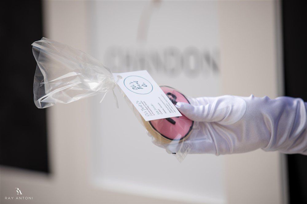 A person wearing white gloves is holding a cookie in a plastic bag.