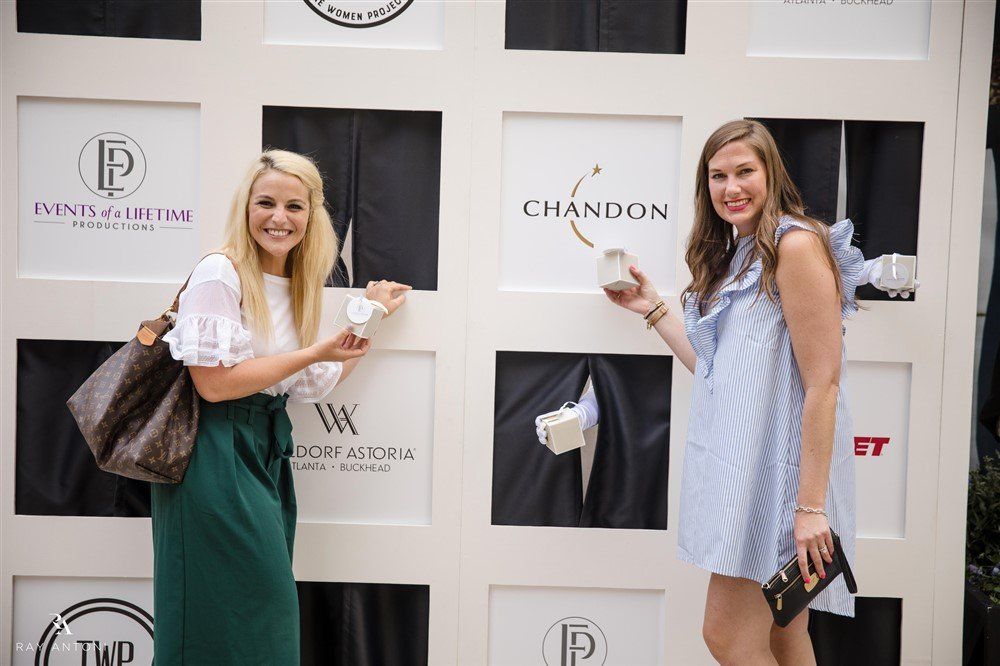 Two women are standing in front of a wall with logos on it.