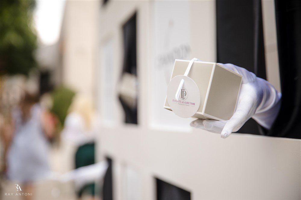 A person wearing white gloves is holding a box in their hand.
