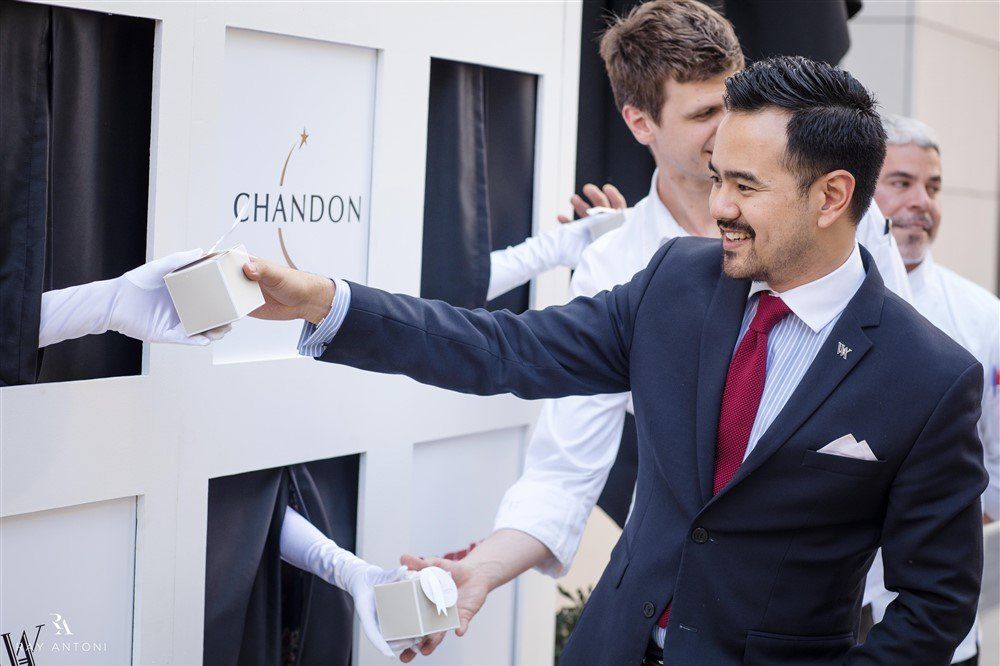 A man in a suit and tie is standing in front of a white box that says chandon.