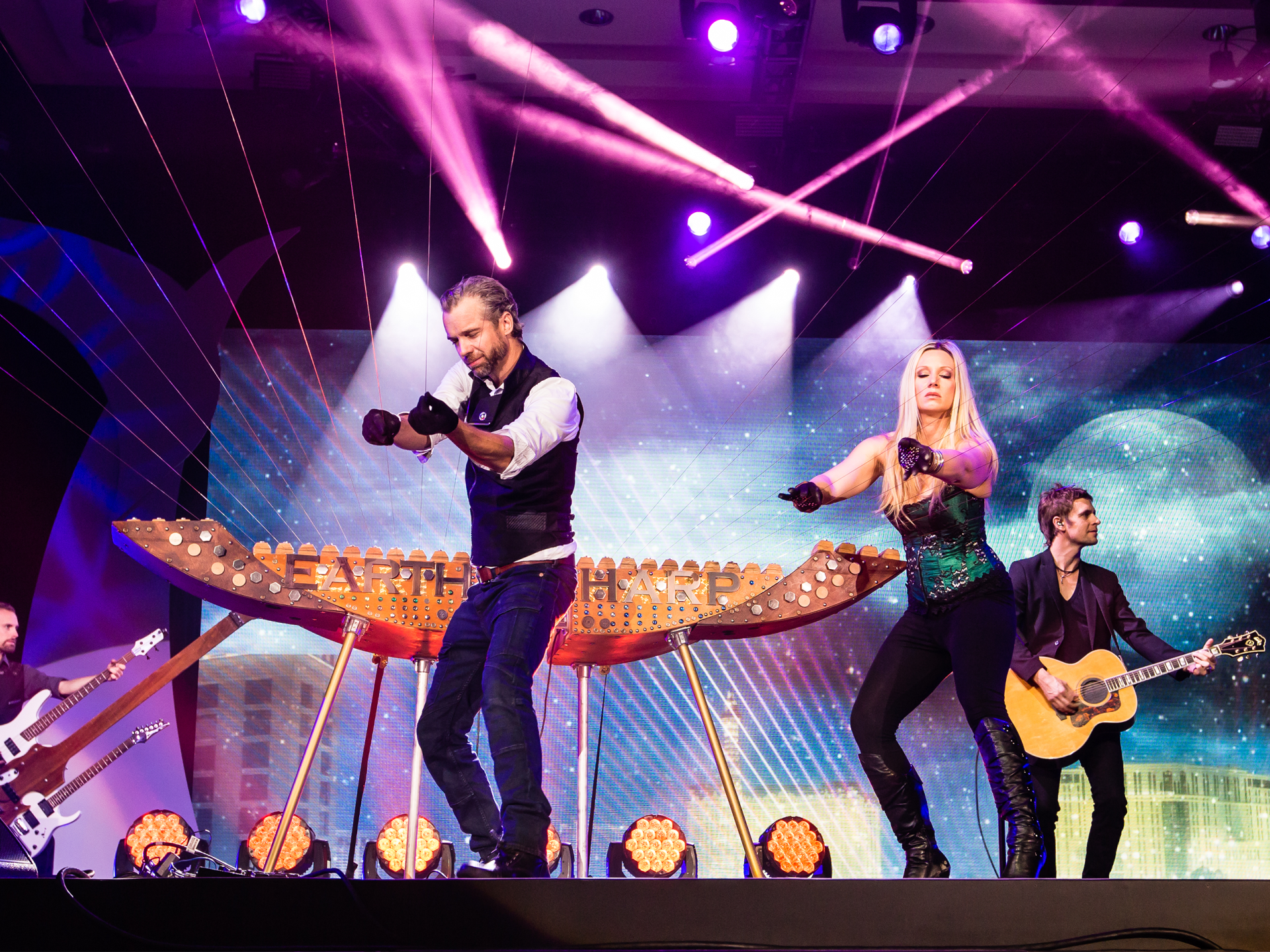 A group of people are standing on a stage playing guitars and dancing.