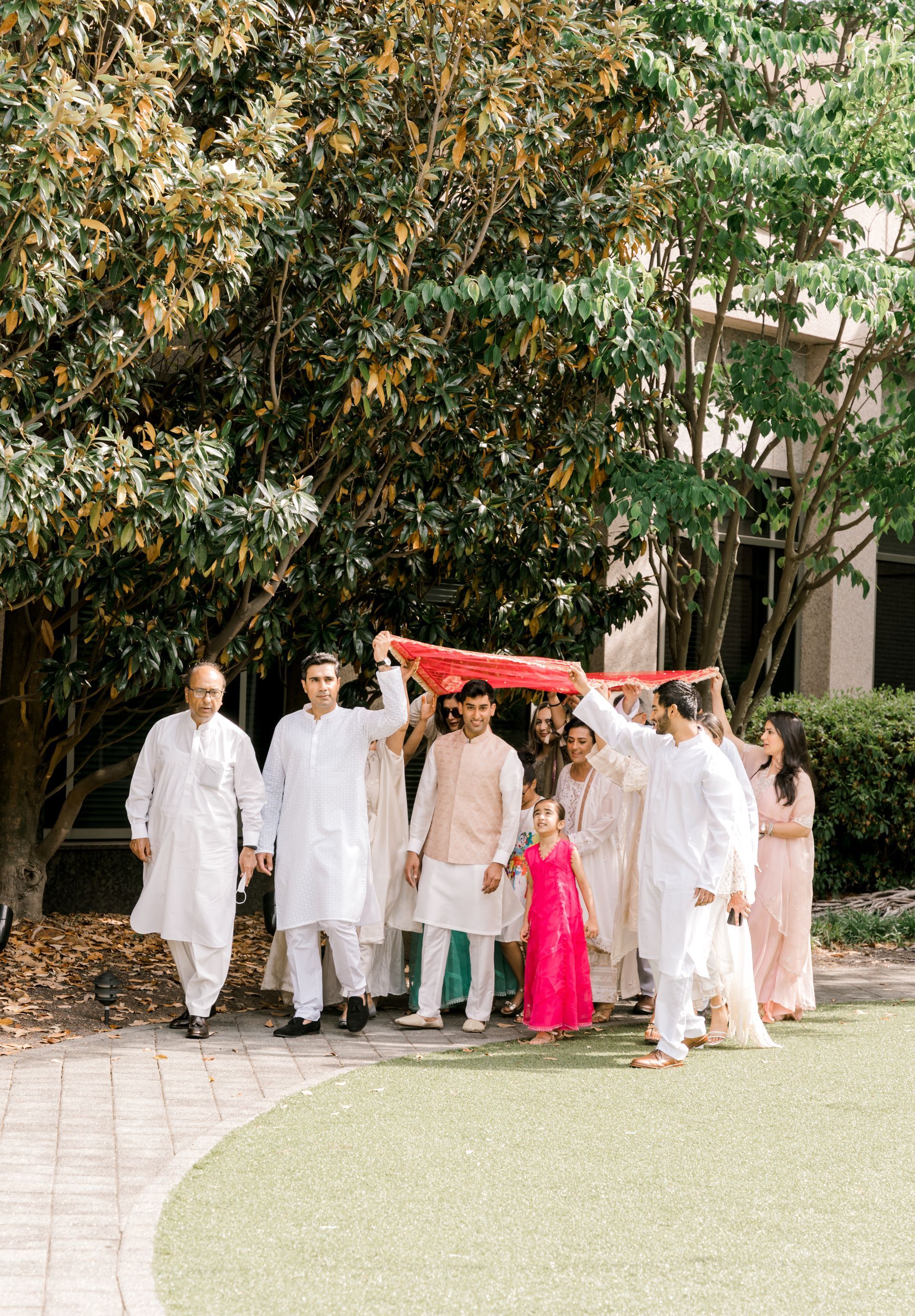 A group of people are walking down a sidewalk holding hands.