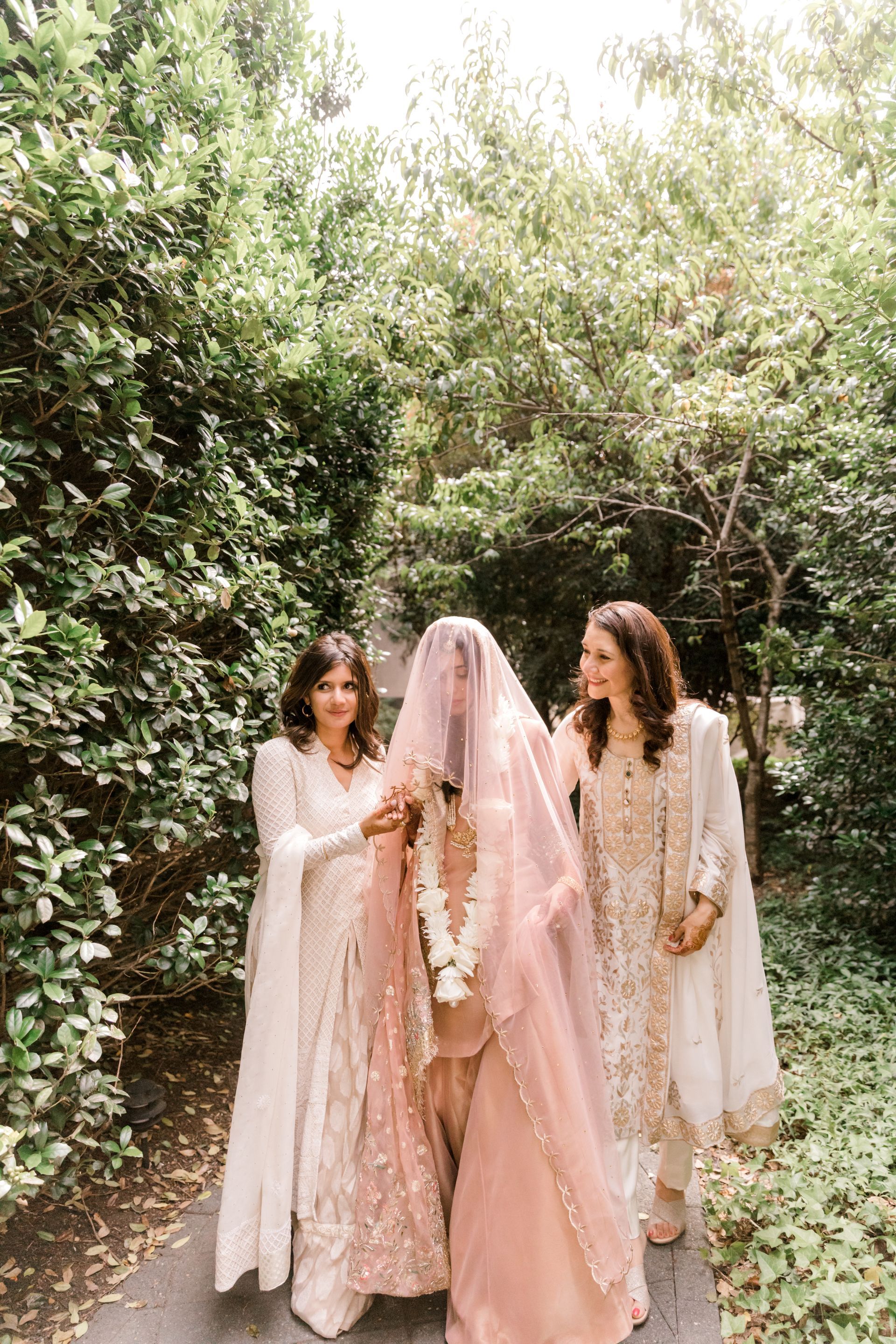 A bride and her mother are walking down a path.