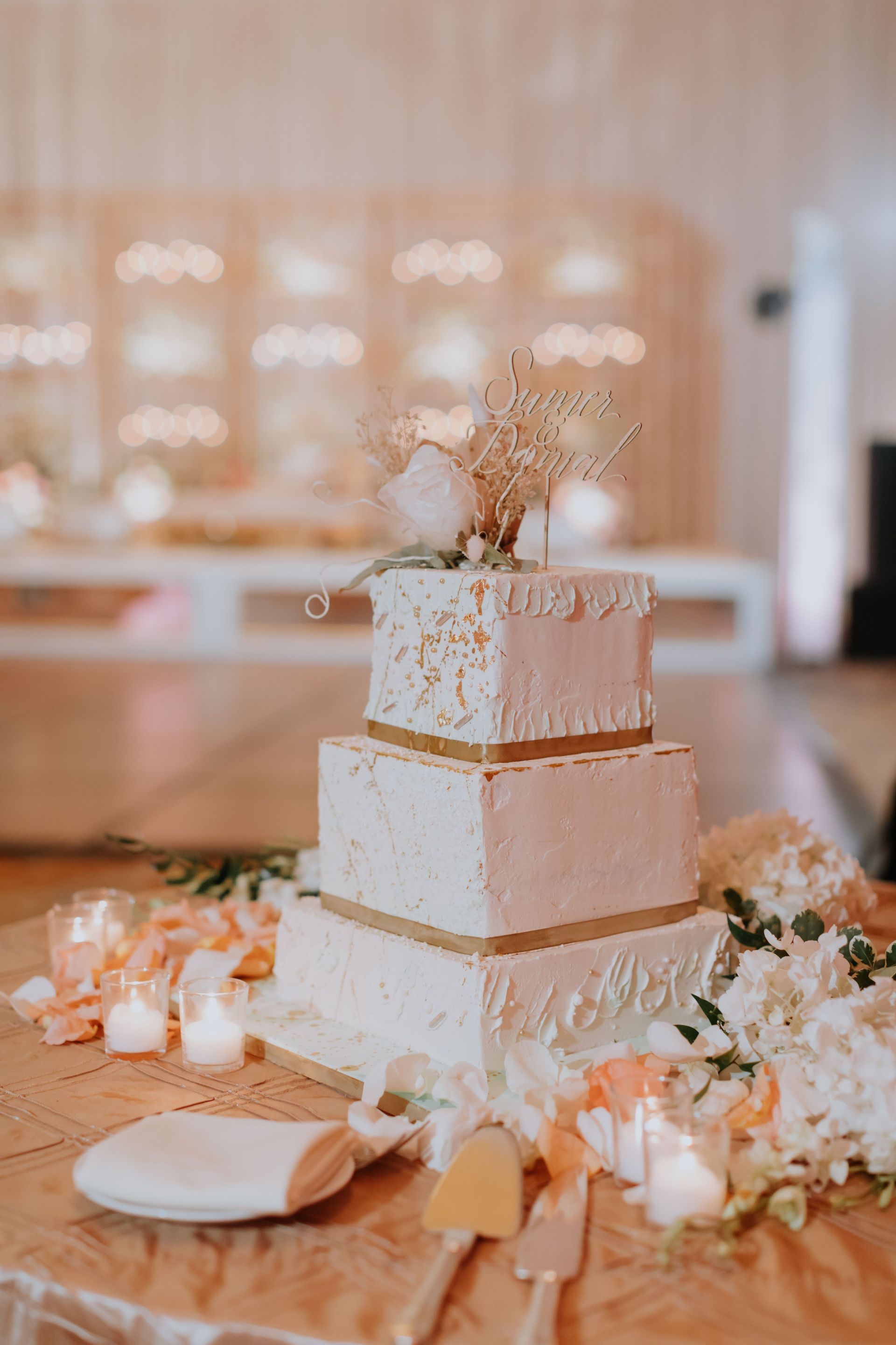 A wedding cake is sitting on a table with candles and flowers.