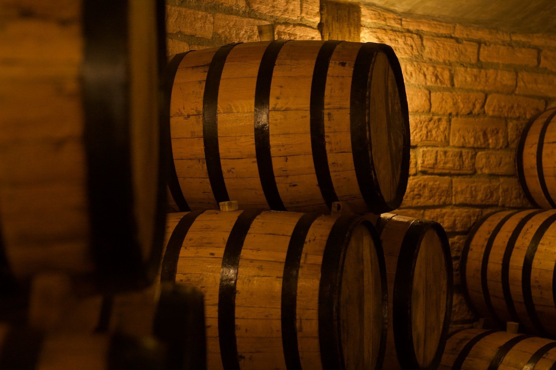 a row of wooden barrels stacked on top of each other in a wine cellar .