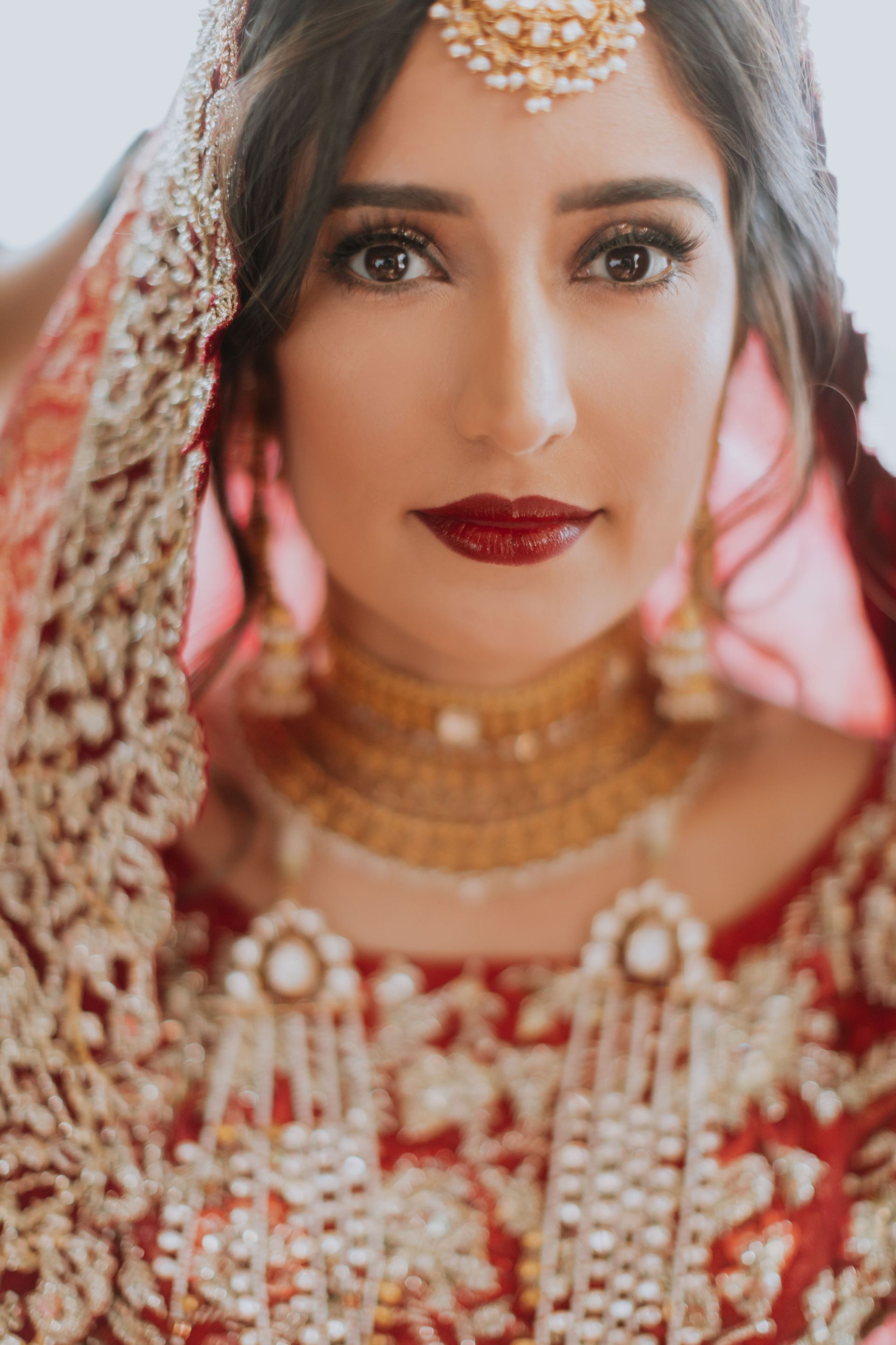 A close up of a woman wearing a red and gold dress and jewelry.