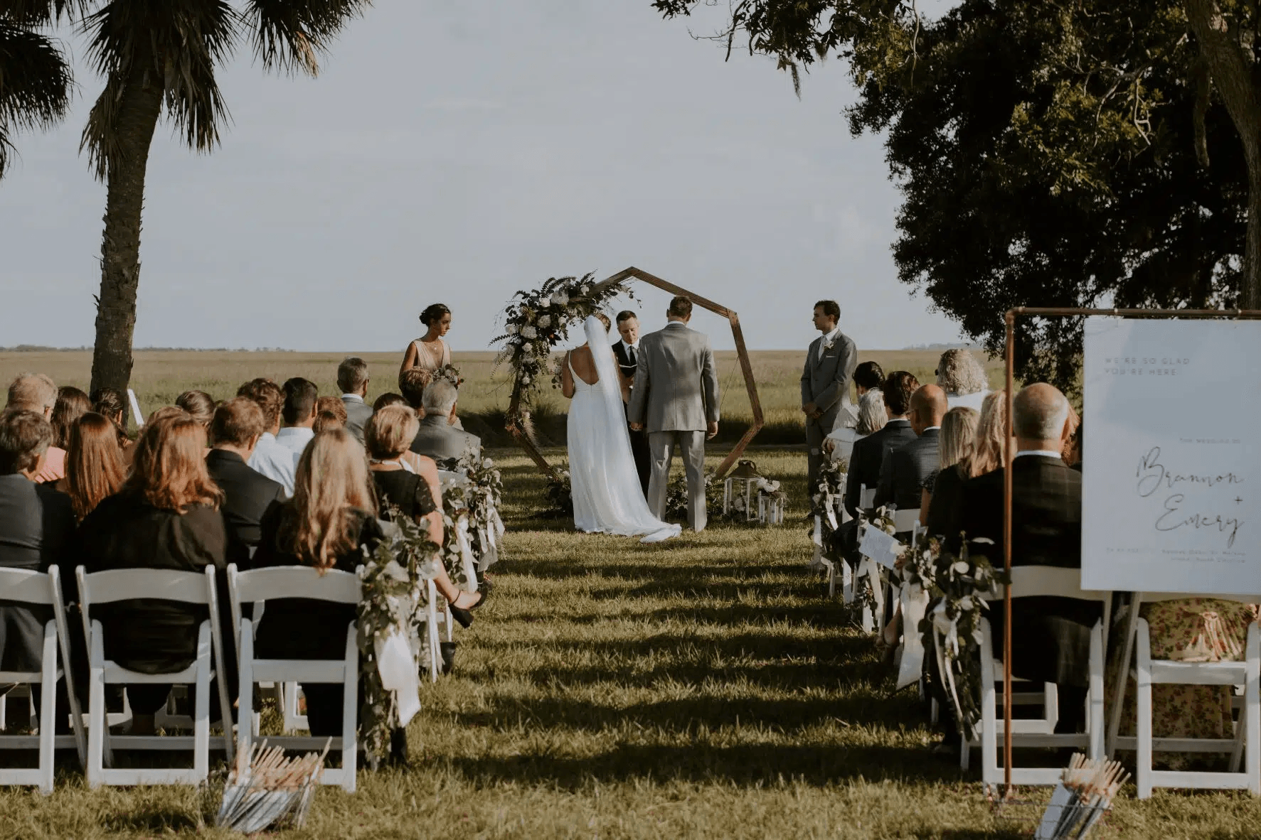 A bride and groom are getting married in front of a crowd of people in a field.