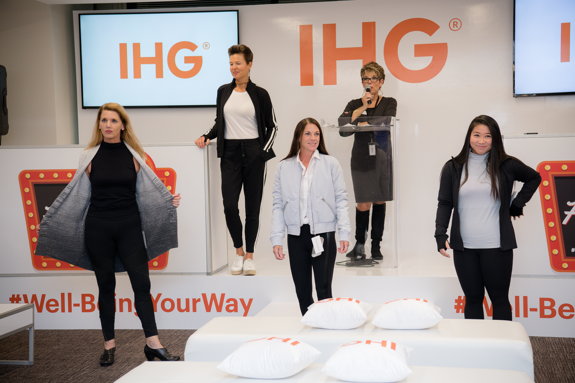 A group of women are standing on a stage in front of a sign that says ihg.