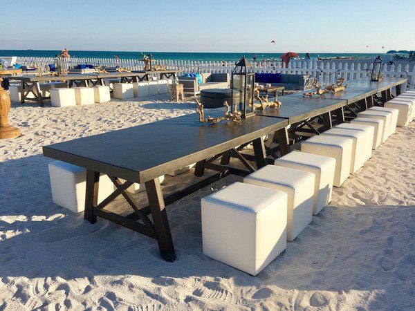 A long table with white ottomans on the beach