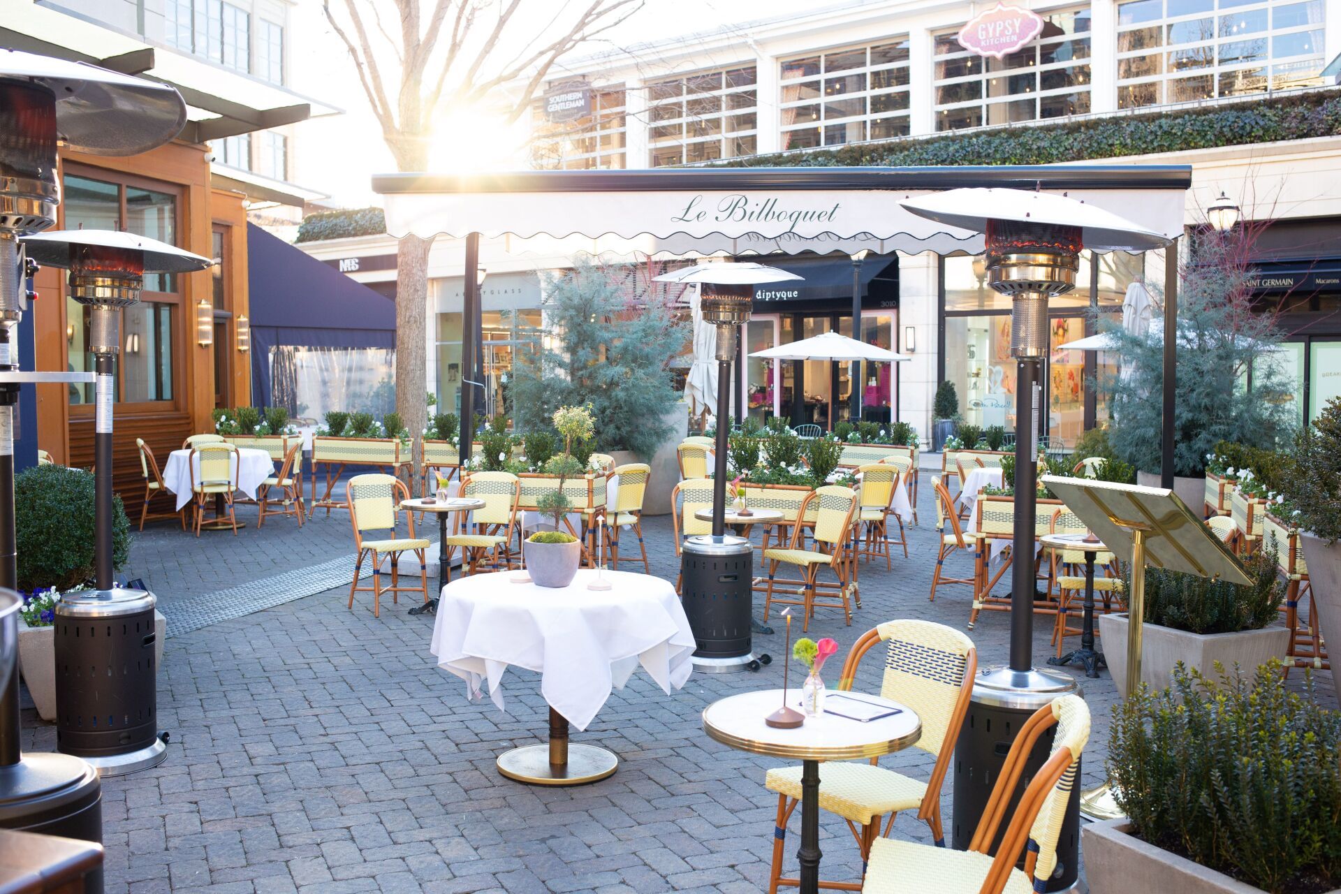 A restaurant patio with tables and chairs and heaters