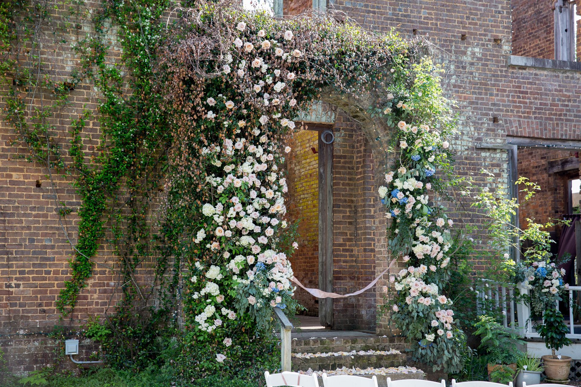 A brick building with a floral arch in front of it.