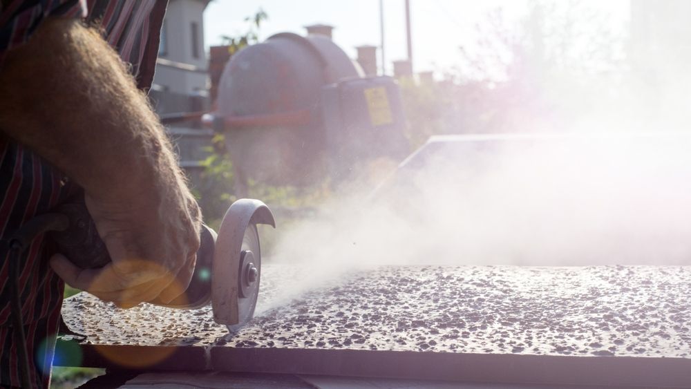 A Man Is Cutting a Piece of Concrete with A Grinder — Hyper Cut & Drill in Swansea, NSW