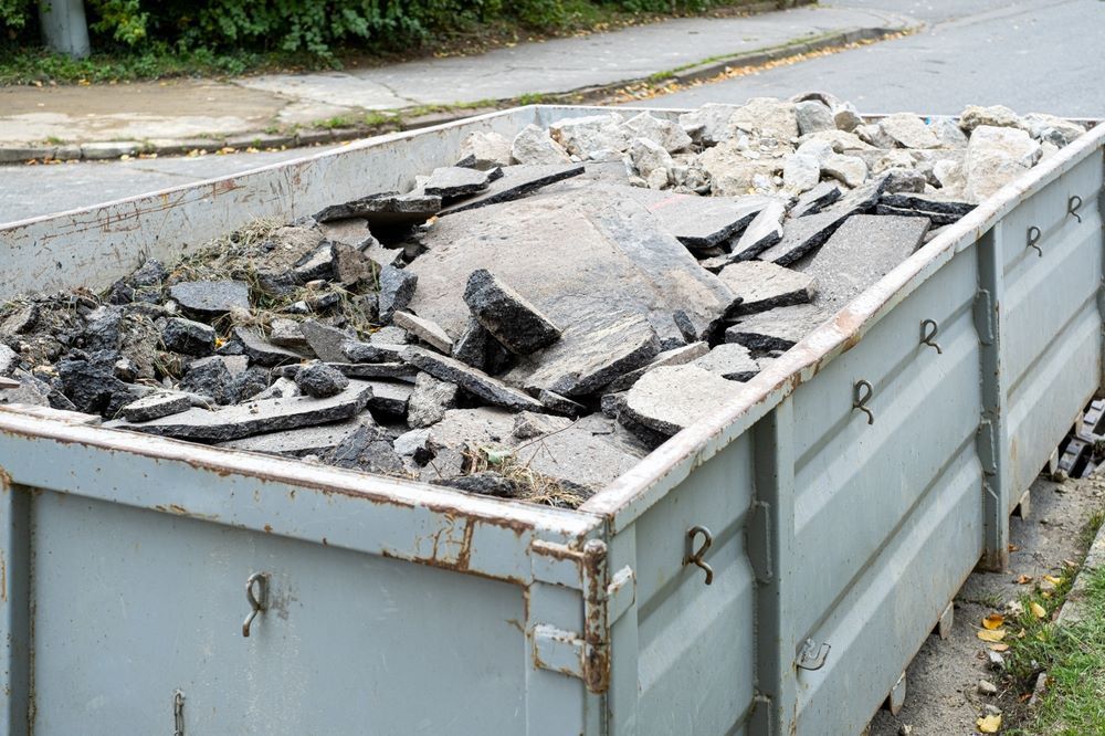 A Dumpster Filled with Rocks and Dirt Is Sitting on The Side of The Road — Hyper Cut & Drill in Newcastle, NSW