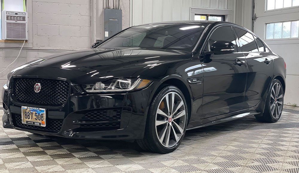 A black jaguar x type is parked in a garage.