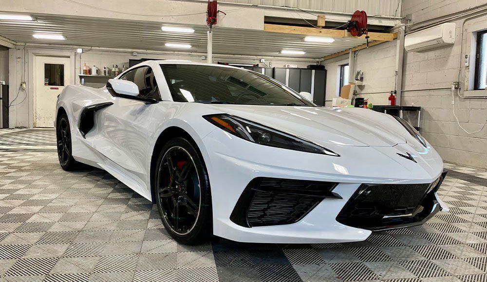A white corvette is parked in a garage.