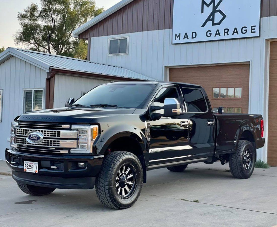 A black pickup truck is parked in front of a garage.