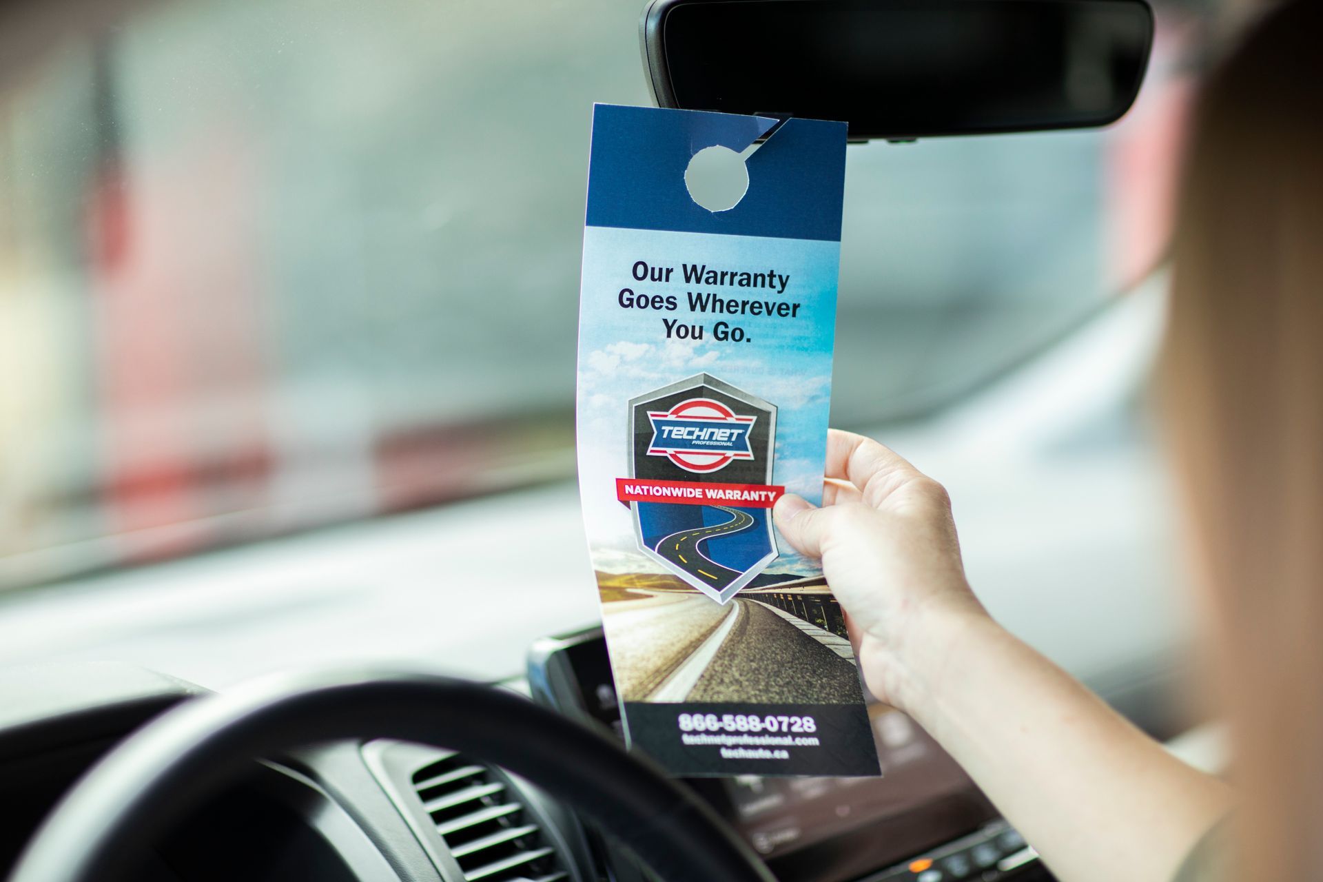 A person in a car holding a flyer that says car mart