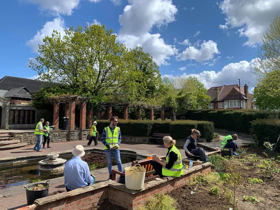 A group of people are working in a garden on a sunny day.