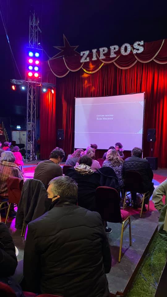 A group of people are sitting in front of a large screen at a circus.