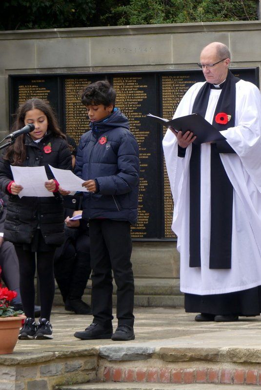 A man in a white robe is reading a book to a group of children
