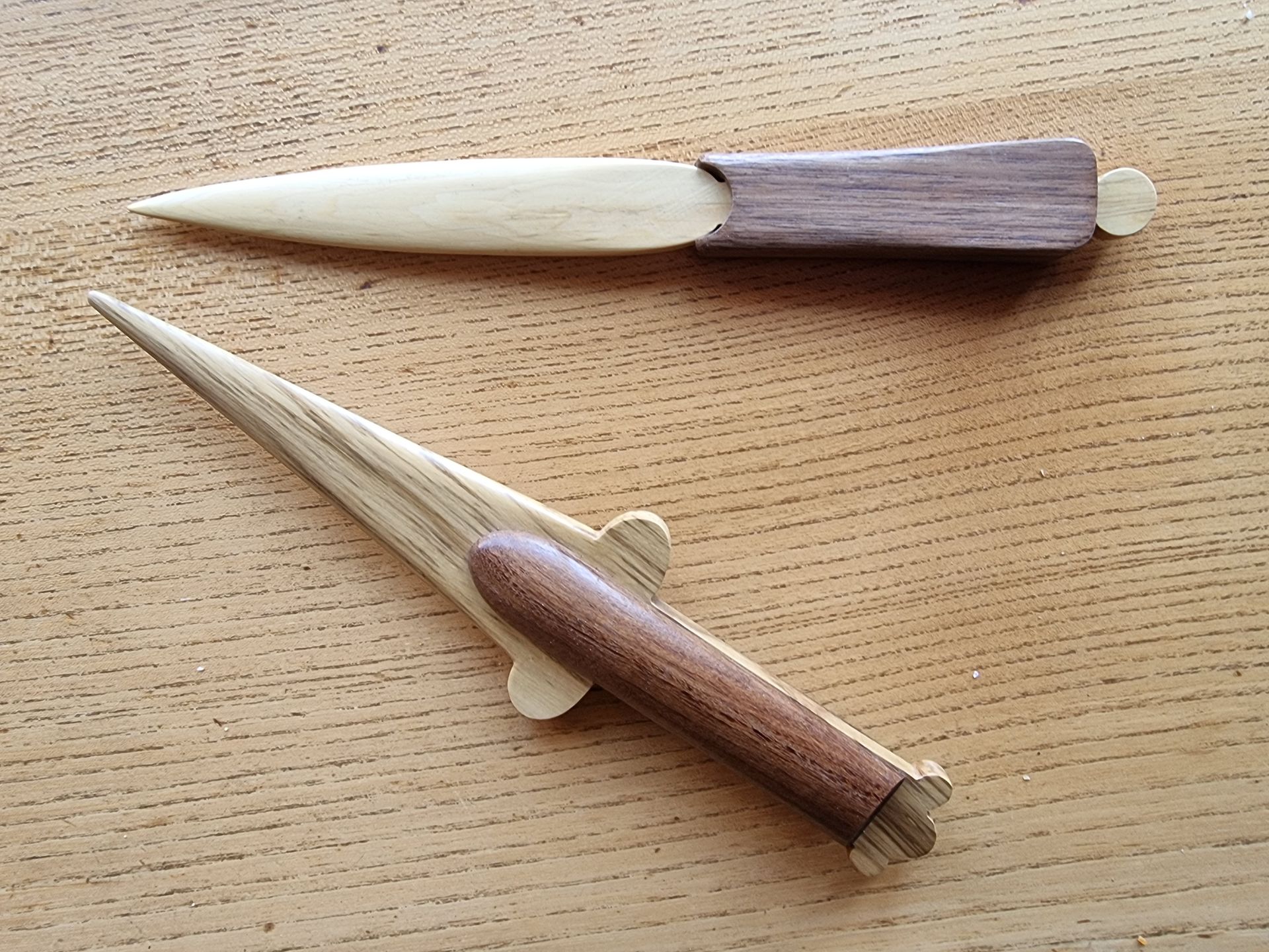 Two wooden knives are sitting on a wooden table.