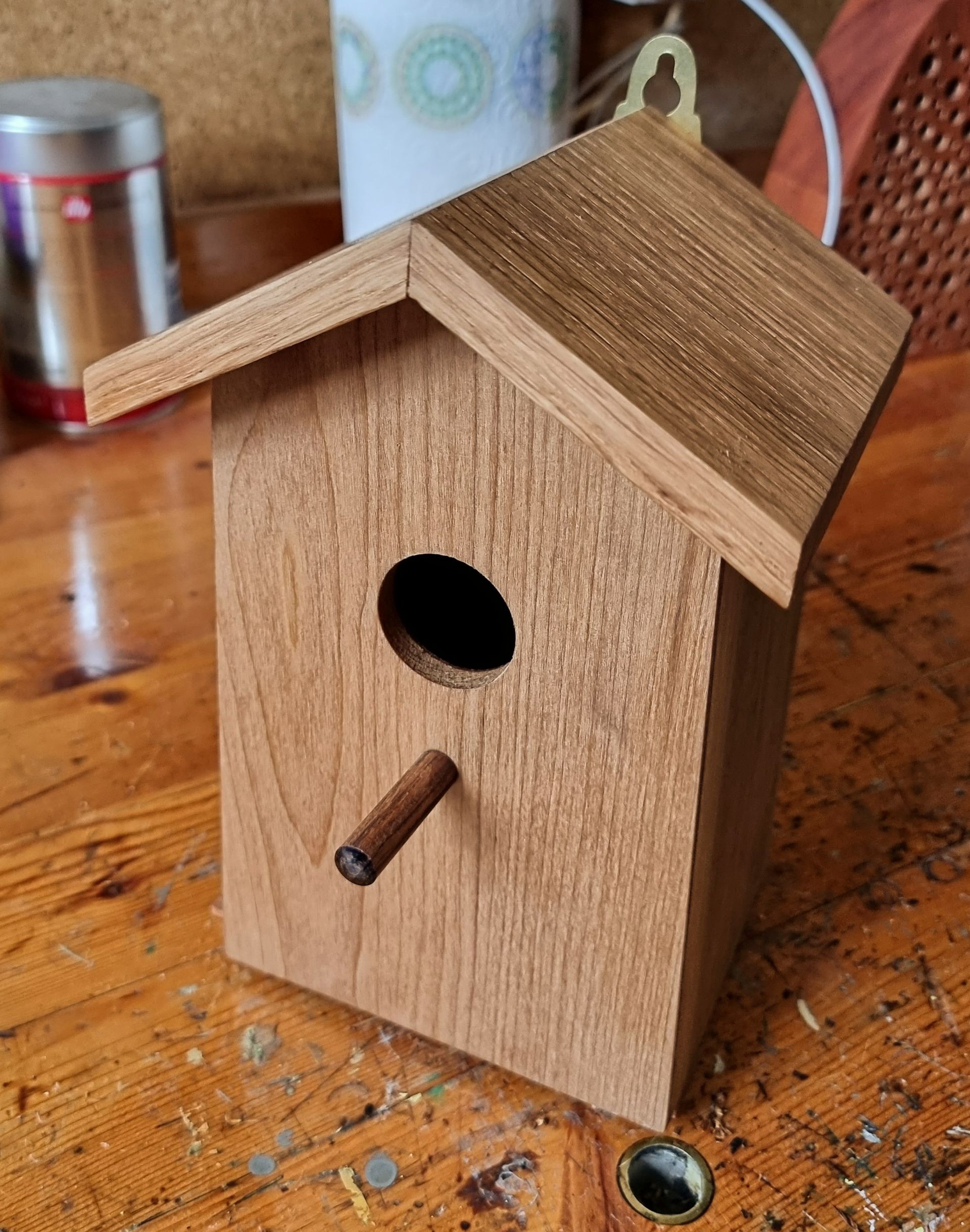 A small wooden birdhouse is sitting on a wooden table.