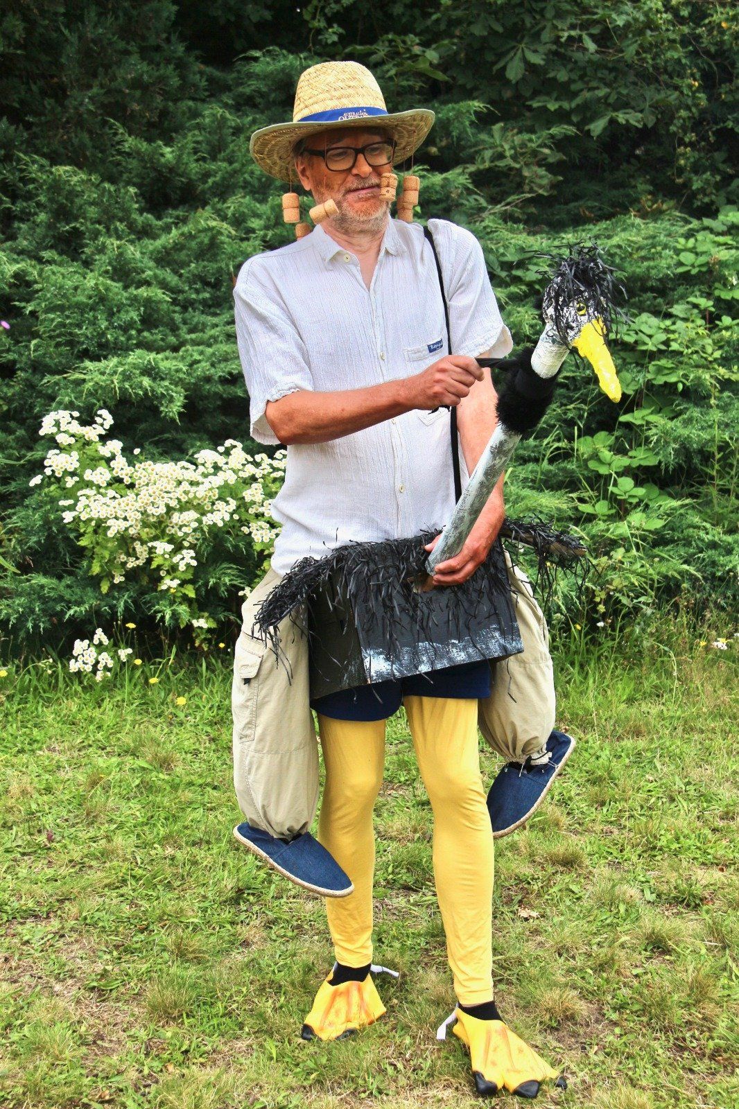 A man in a straw hat is carrying an ostrich on his back.