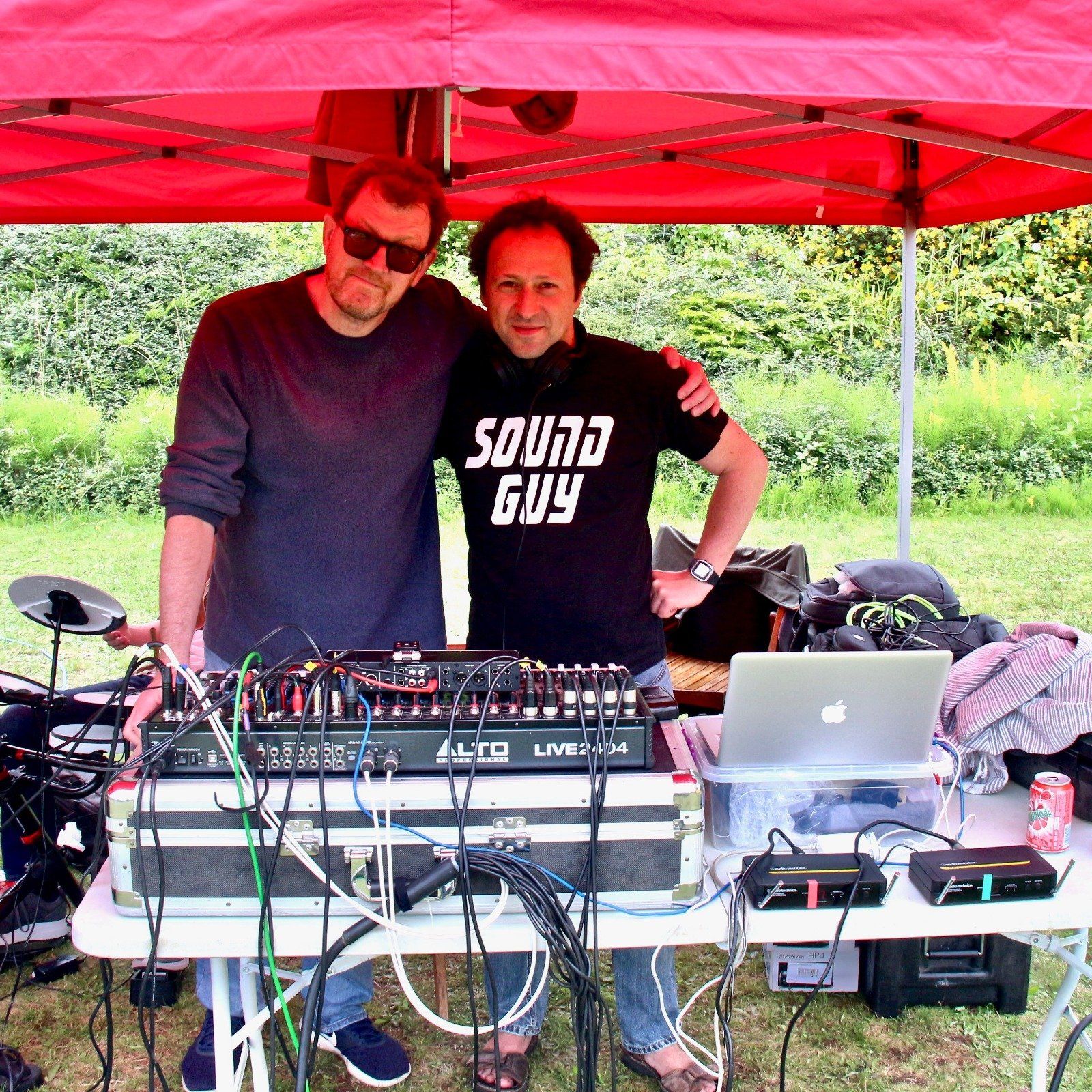A man wearing a shirt that says sound guy stands next to another man