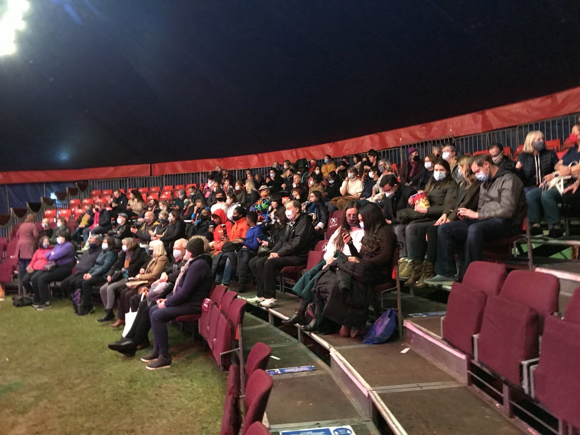 A large group of people are sitting in a circus big top watching a show.