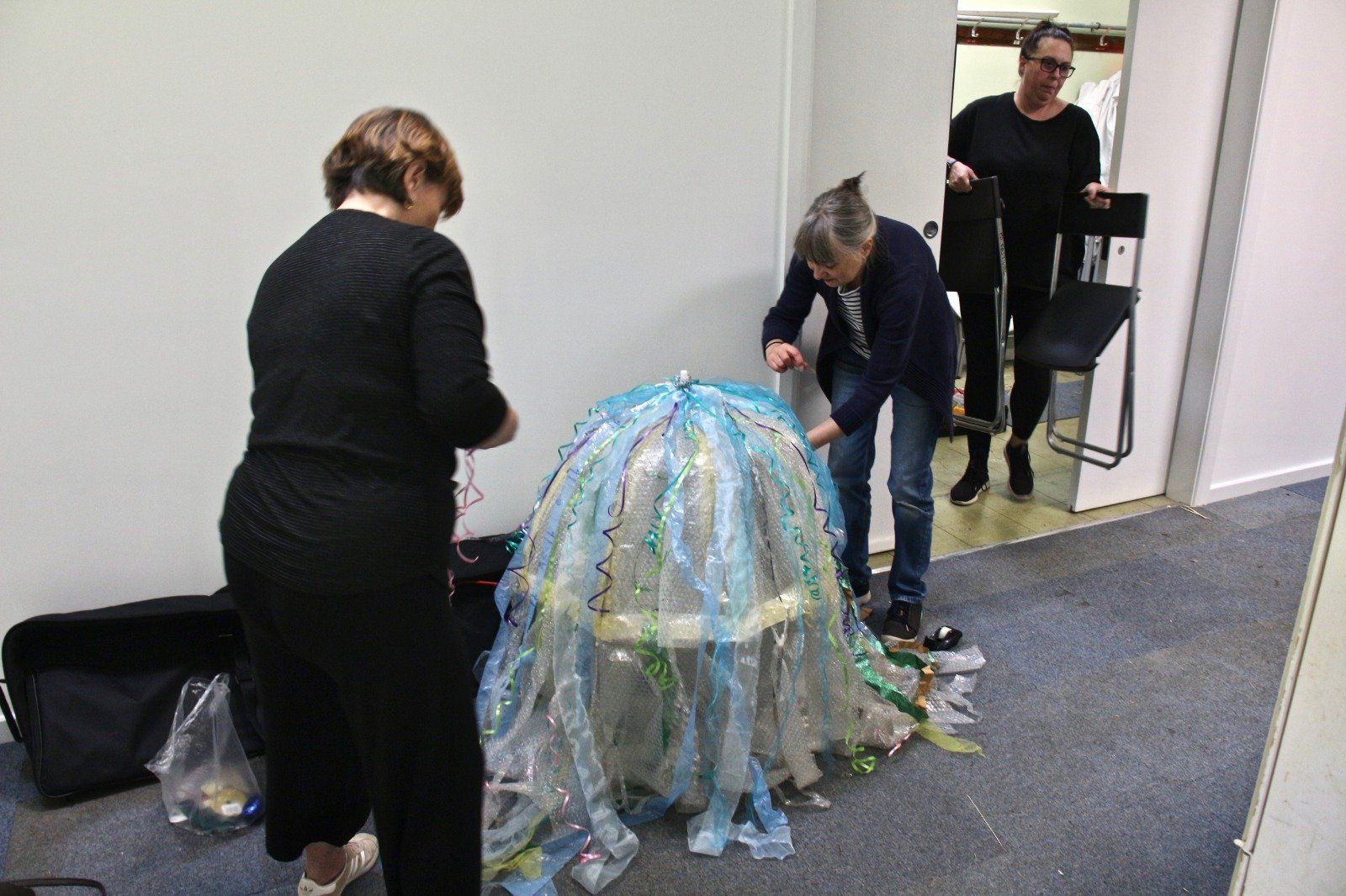 A group of people are standing around a large object in a room.