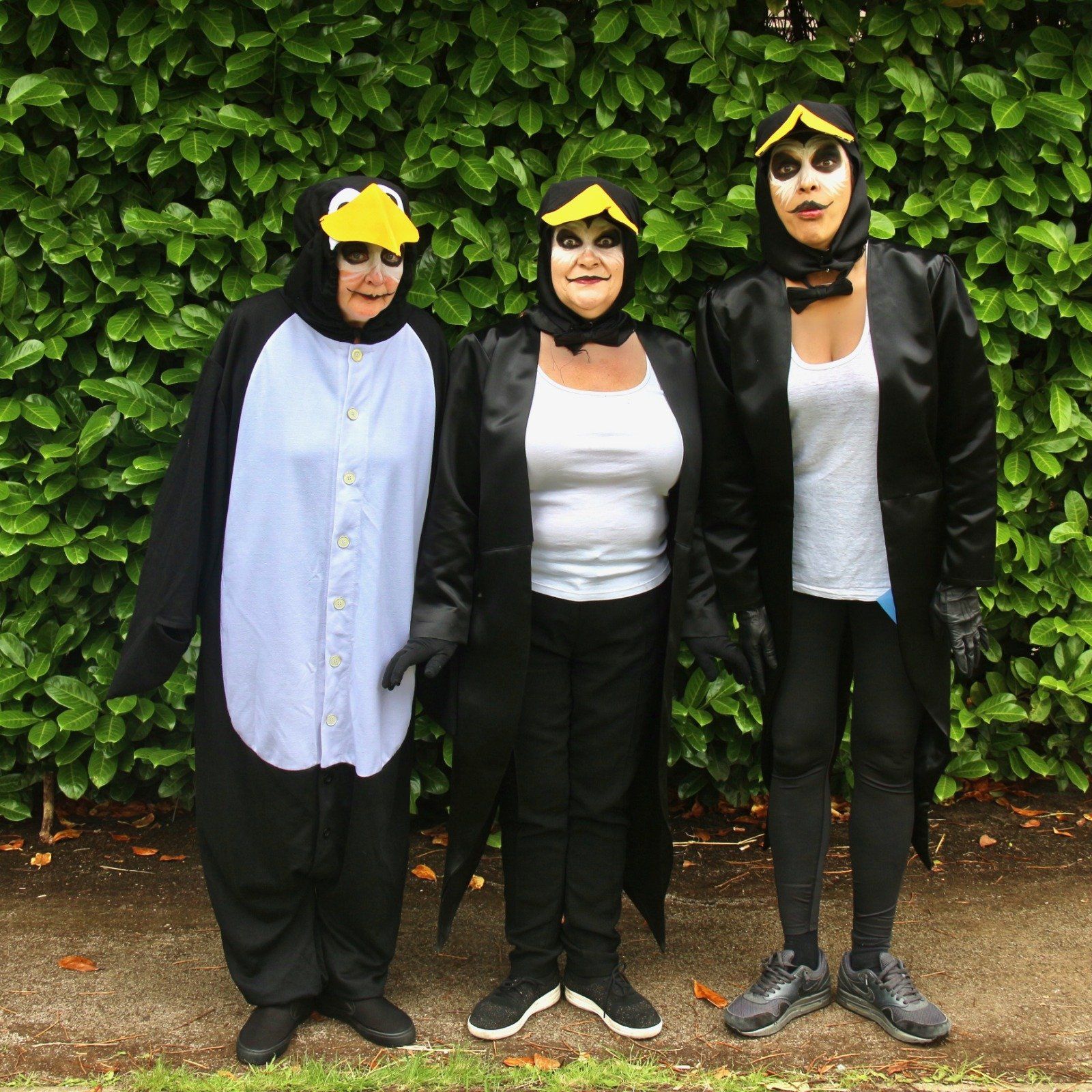 Three women dressed in penguin costumes are posing for a picture