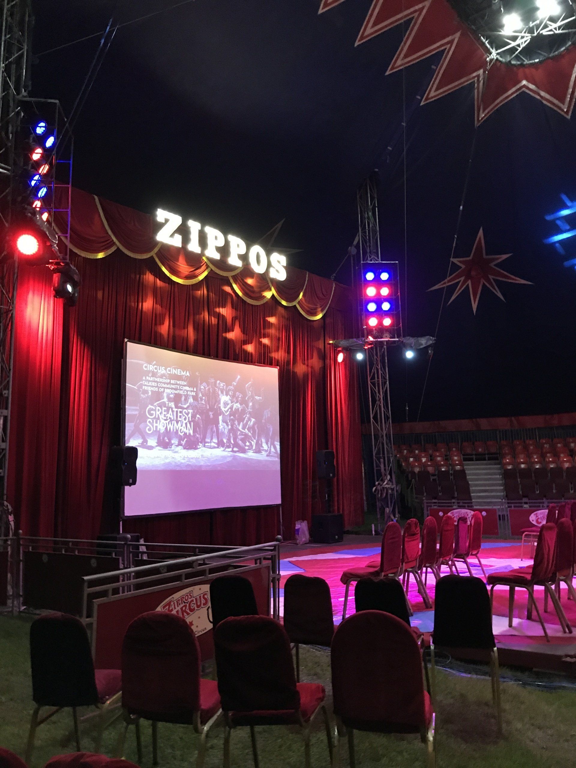 A circus with a large screen and a sign that says zipros