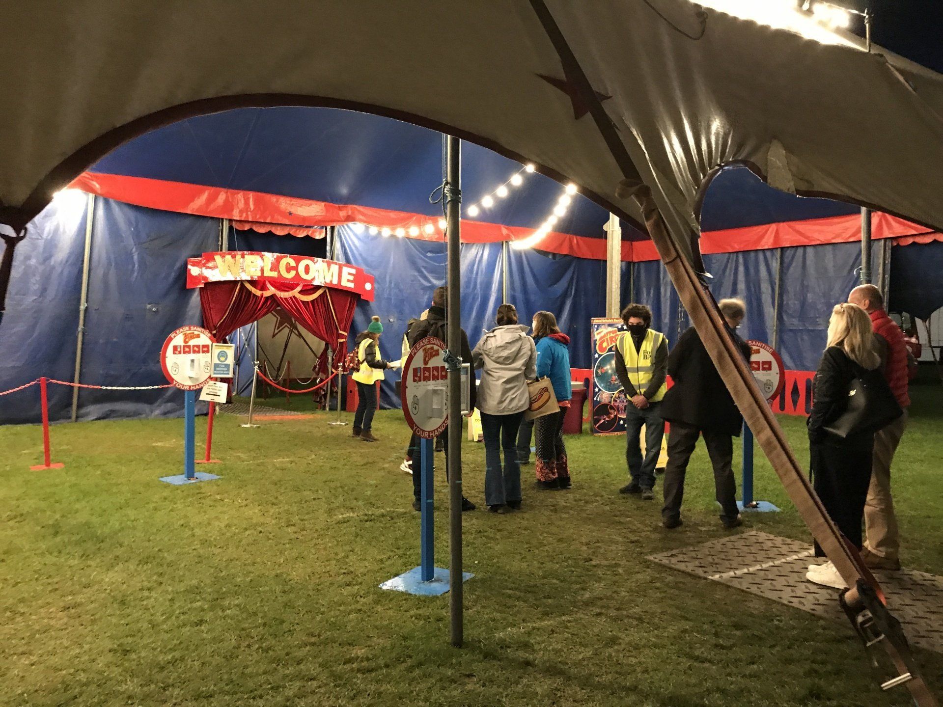A group of people are standing outside of a circus tent.