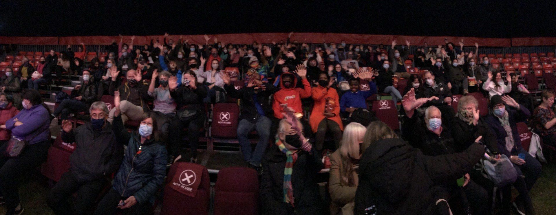 A crowd of people are sitting in a circus big top watching a movie.