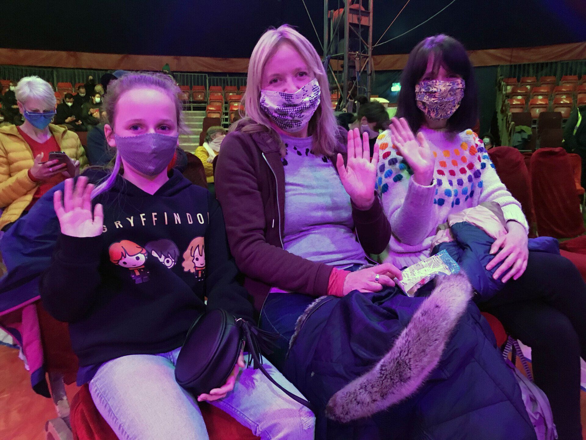A group of people wearing face masks are sitting in a circus.