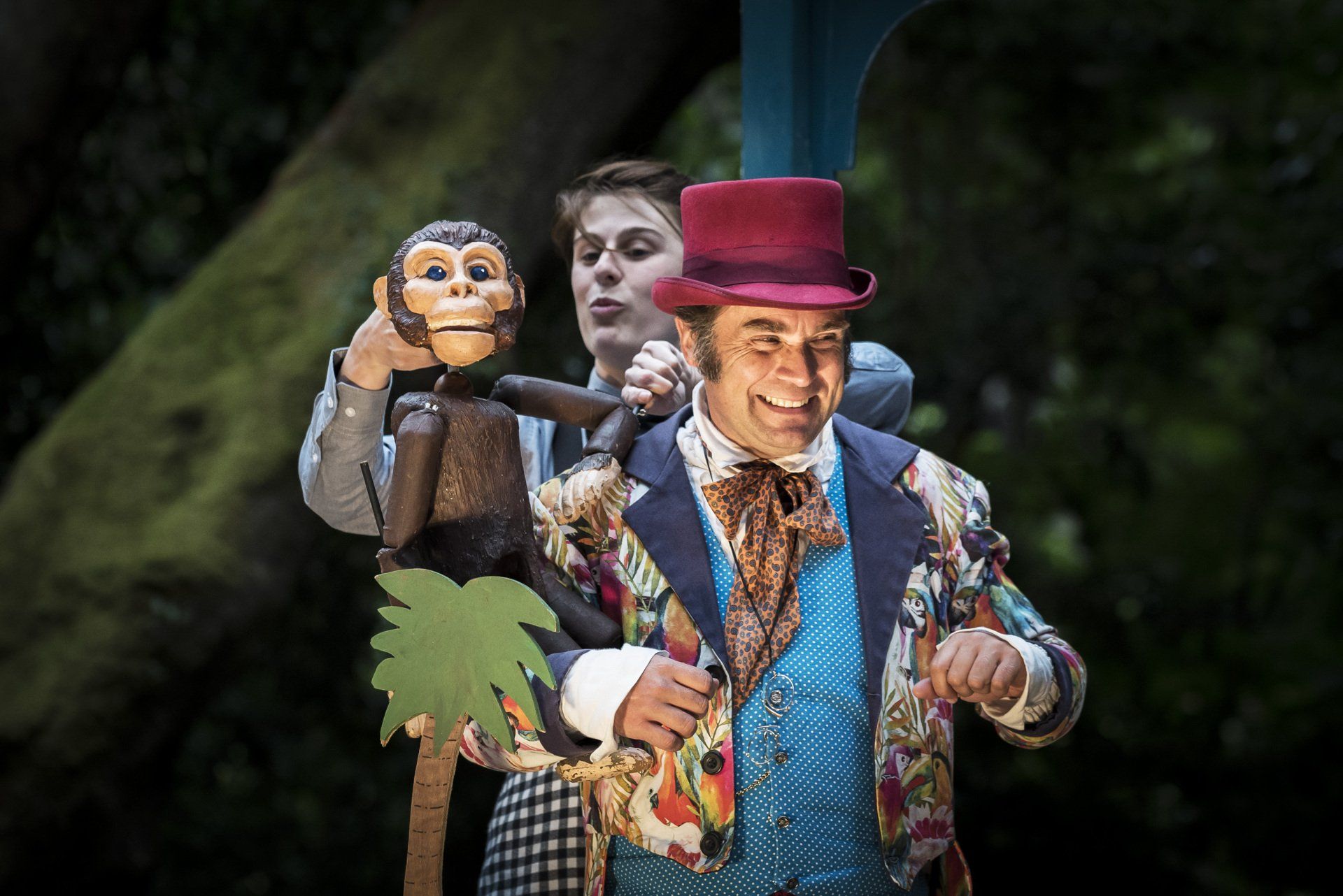A man in a top hat is holding a monkey puppet.