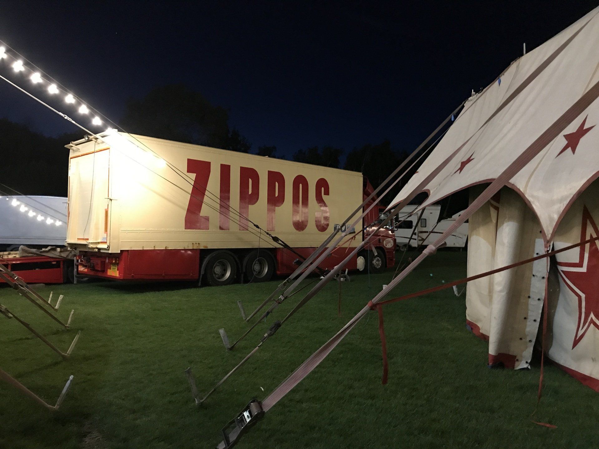 A truck with the word zippos on it is parked next to a tent.