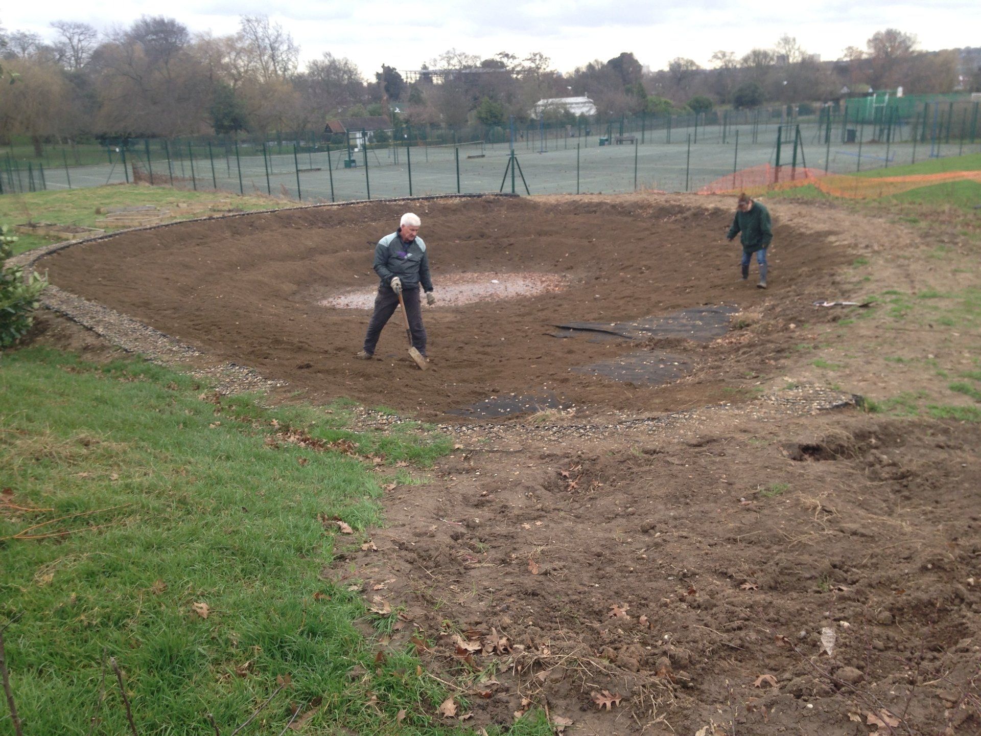 A man is standing in the middle of a dirt field