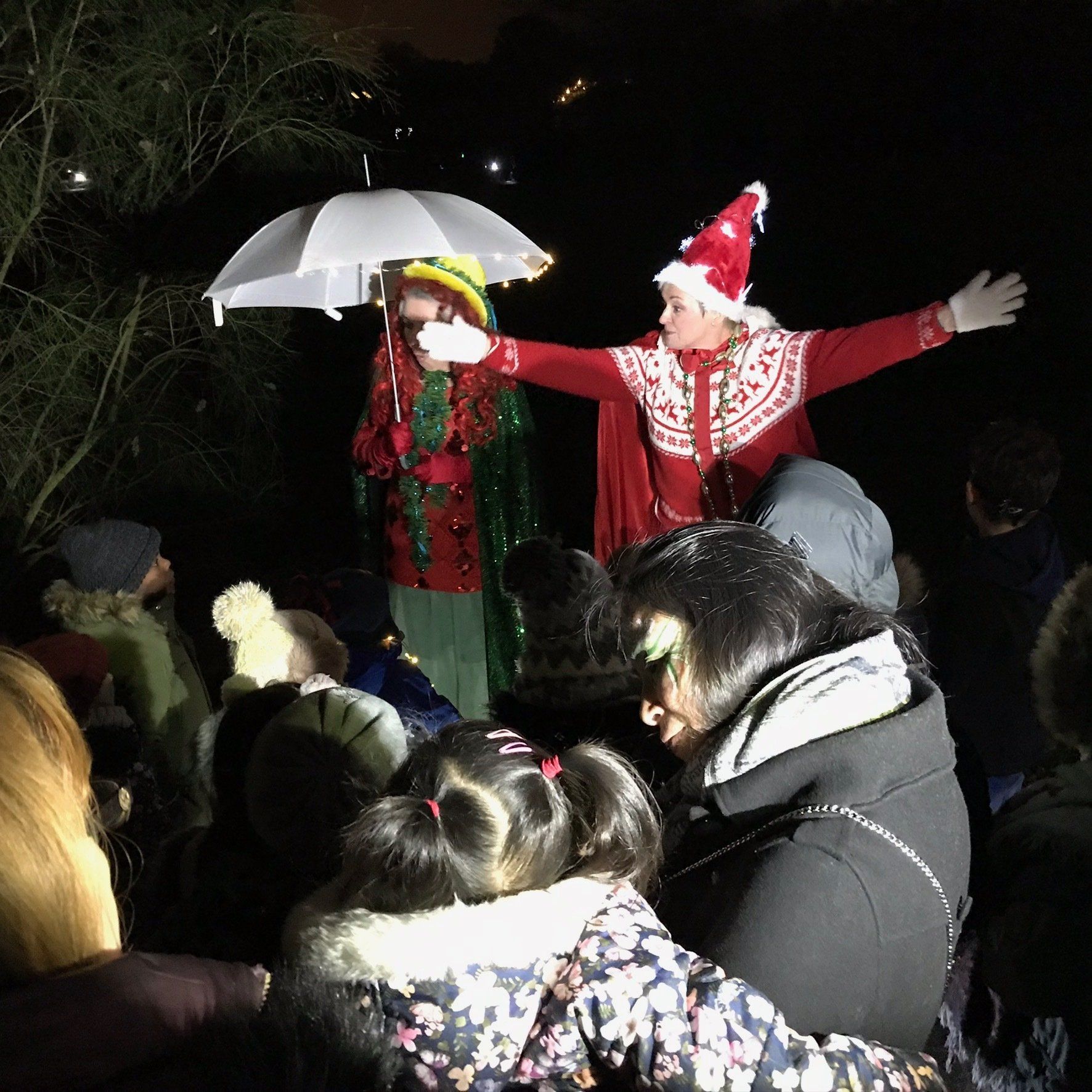 A man in a santa hat is holding an umbrella over a group of people