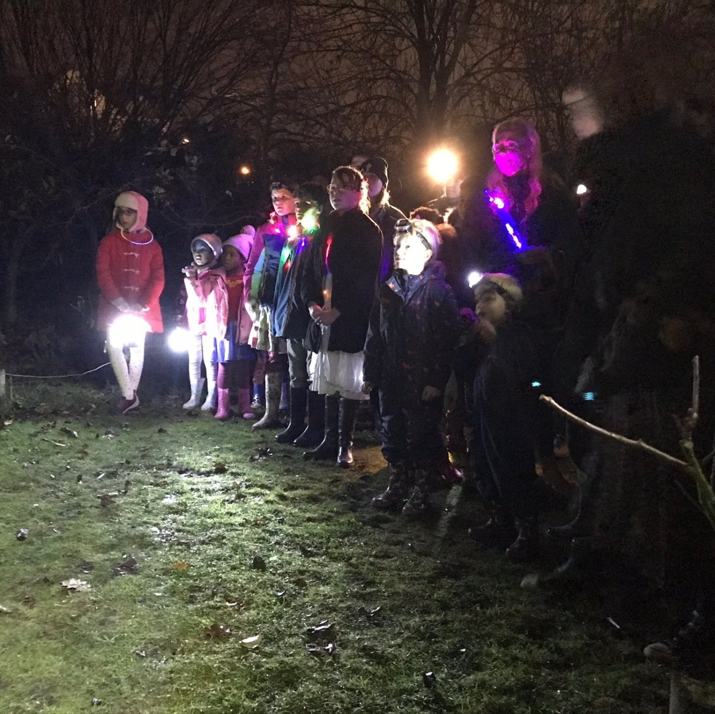 A group of people are standing in a line holding flashlights