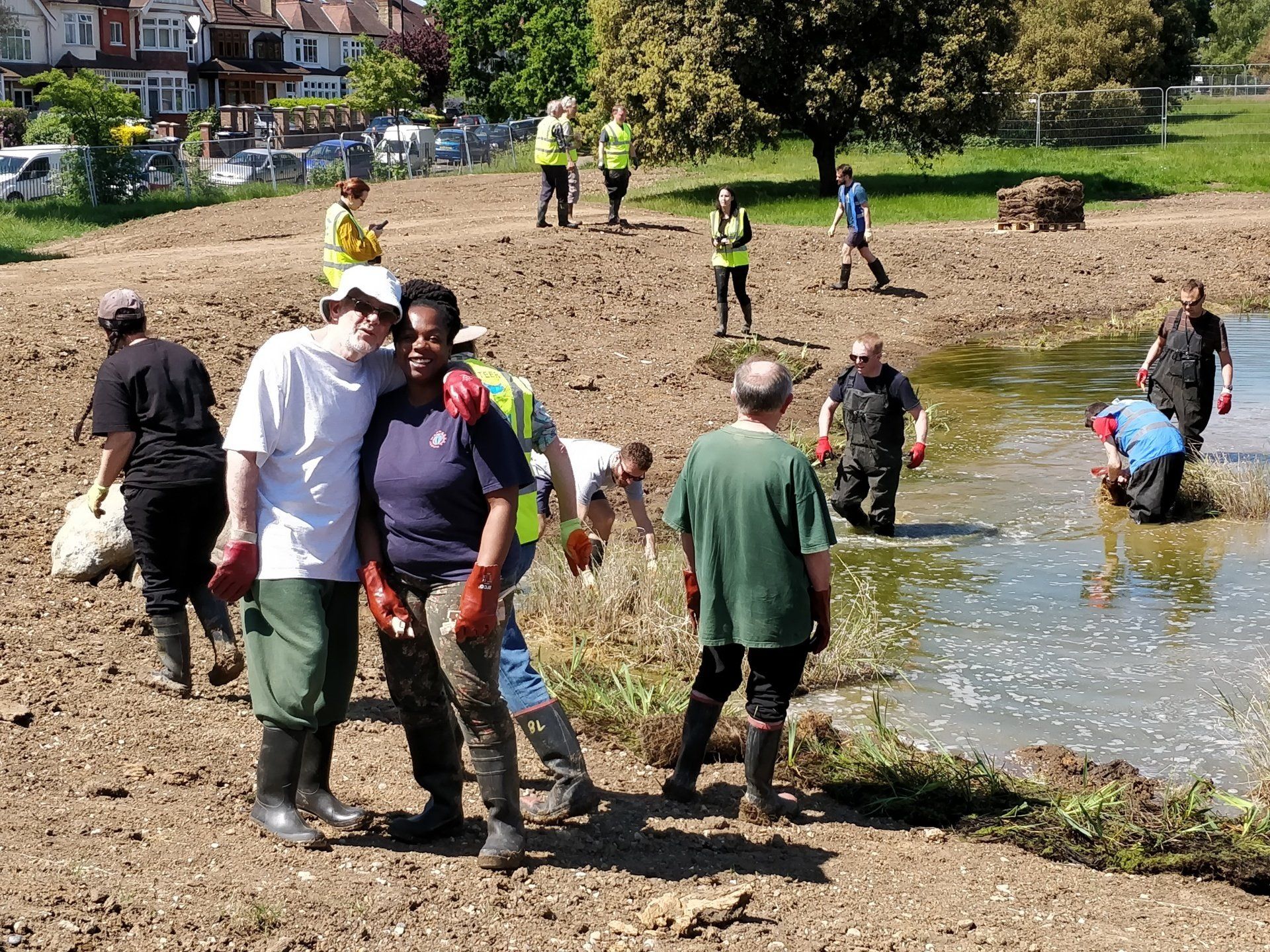 A group of people are standing in the dirt near a body of water.