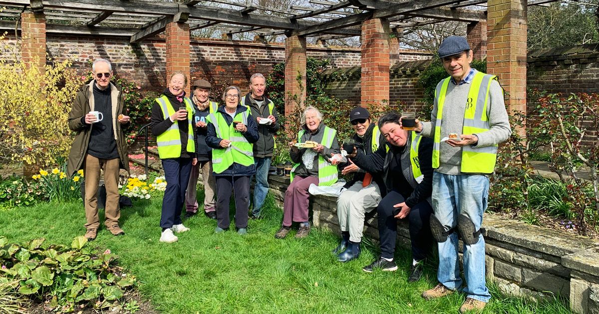 A group of Friends of Broomfield Park volunteers, wearing HiVis vests are standing in the park.