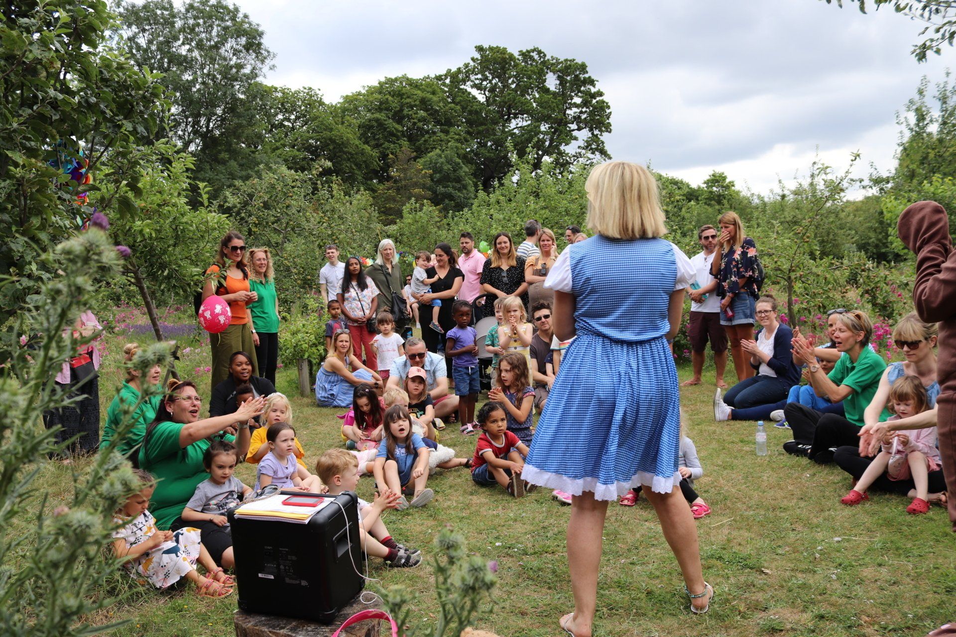 A woman in a blue dress is standing in front of a crowd of people.