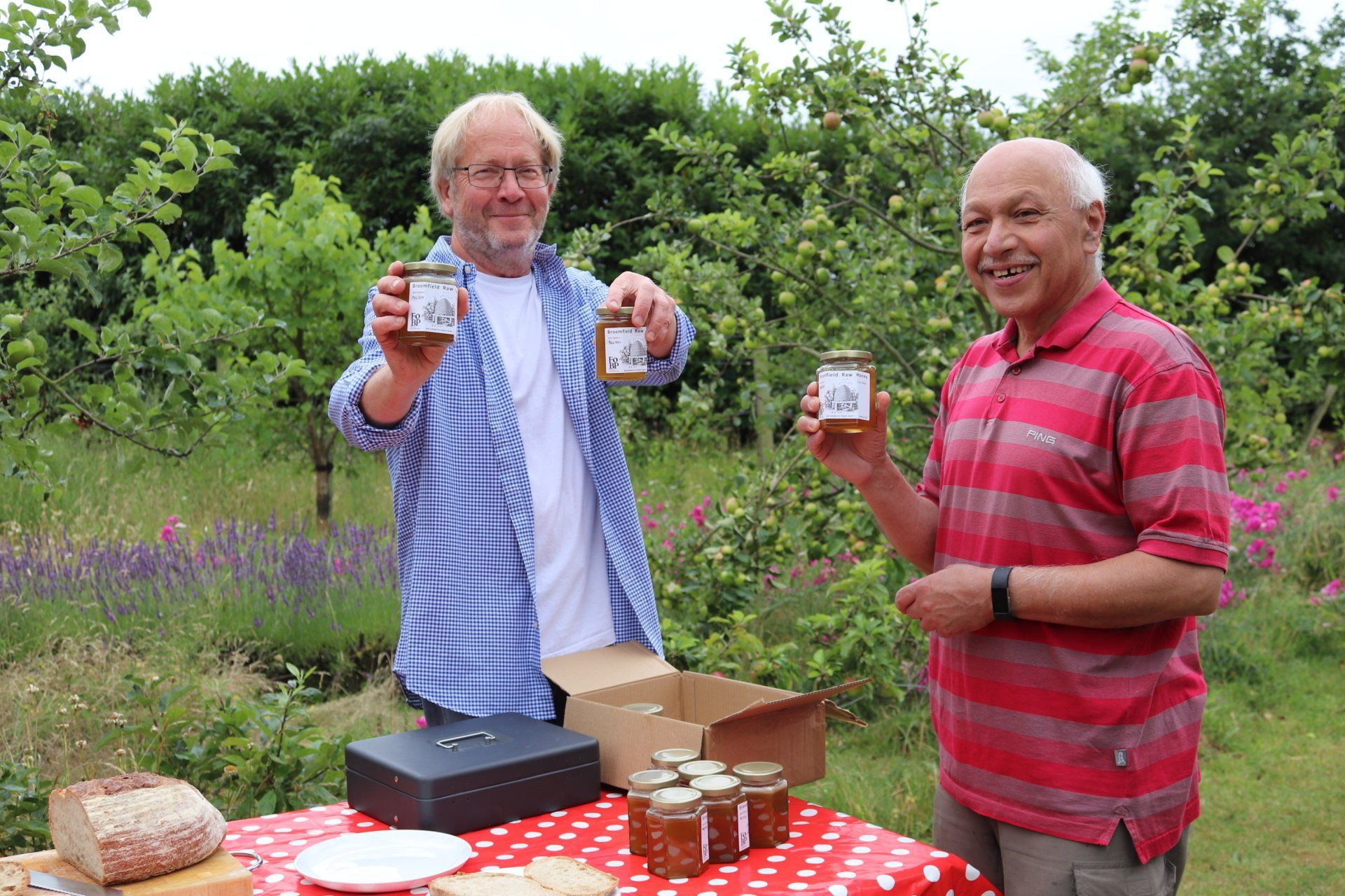 Two men standing next to each other holding jars of jam